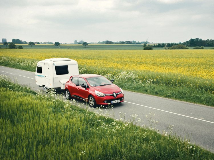 Bil med campingvogn kører på vej om sommeren. 